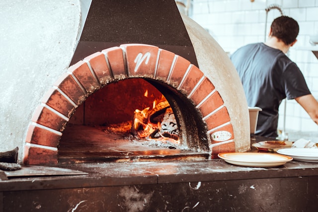 Pizzaiolo enfournant une pizza sur un corner de restauration lors d'un événement privé